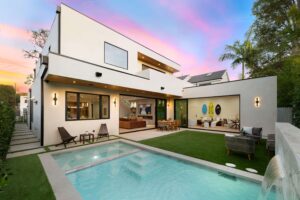 Contemporary two-story home with spacious outdoor patio, private pool, seating area, and large windows, showcasing stylish home extensions and modern design