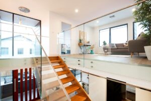 Home renovations showcasing a modern two-level interior with wooden stairs, glass balustrades, and a bright living area with contemporary furniture and large windows.