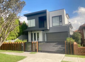 Modern two-storey home with contemporary grey facade, double garage, and secure front fencing