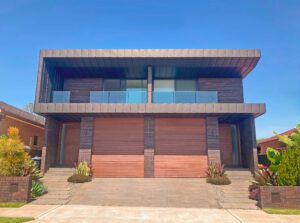 Modern two-storey brick home with double garage, glass balcony, and contemporary architectural design
